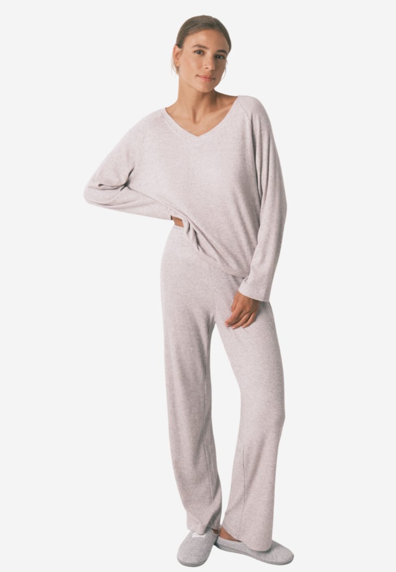 Lys grå loungewear sæt bestående af en V-hals langærmet top og matchende brede bukser, lavet af blødt, struktureret stof.