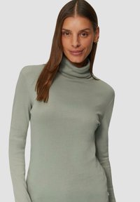 Jasnozielony sweter z golfem, wykonany z miękkiego materiału, z długimi rękawami i dopasowanym krojem o gładkiej fakturze.