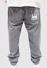 Hallide denim püksid, millel on lõdva istuvusega lõige, sisaldavad kahte tagumist taskut, millest üks kannab krooni logo ja teine punast silti. Lõdvad lõhikud.
