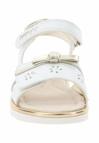 Sandal de cuero blanco con un lazo de acento dorado, recortes florales en la correa y una plantilla acolchada beige. Suela plana con ribete dorado.