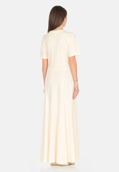 Abito maxi color crema a maniche corte realizzato in tessuto morbido e leggero. Vestibilità fluida e rilassata con una texture liscia e un design semplice.