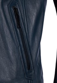 Marineblaue Lederjacke mit einem diagonalen Reißverschluss und mattem Finish, strukturierter Oberfläche und eleganten Designdetails in der Nähe der Tasche.