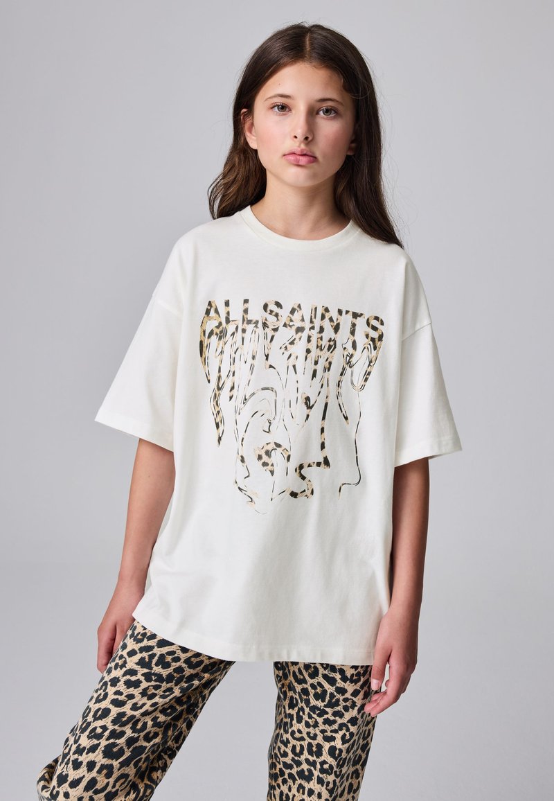 Witte oversized t-shirt met luipaardprint, korte mouwen en een ronde hals. Gecombineerd met een broek met luipaardprint.