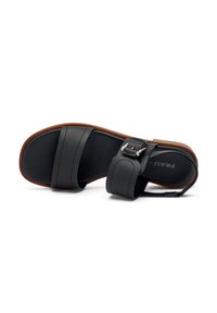Sandal nera in pelle con due cinturini larghi, un cinturino alla caviglia con fibbia e una suola in gomma marrone. Caratterizzata da una texture liscia e un design minimale.
