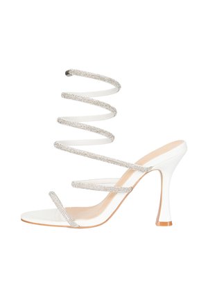 Hvid højhælet sandal med flere tynde, glitrende remme inklusive en spiralformet ankelrem og en beige sål med en spids hæl.