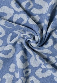 Tissu bleu présentant un motif léopard clair, avec une texture douce et une forme tourbillonnante et pliée.