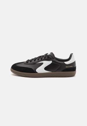 Czarno-biały niski sneaker marki Skechers z brązową podeszwą, czarnymi sznurówkami i złotym logo Skechers na tylnej części buta.