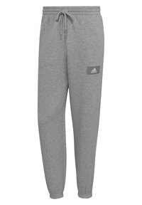 Šedé tepláky vyrobené z jemné tkaniny, s žebrovaným nápletem u kotníků a elastickým pasem. Obsahují malou šedou nášivku s logem Adidas.
