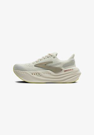 Baskets de course légères de couleur blanc cassé avec une tige texturée, une semelle flexible et une semelle extérieure jaune contrastante. Présence d'une marque sur le côté.
