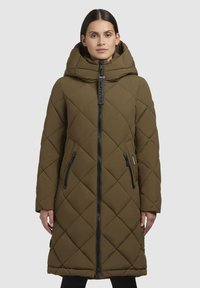 Parka căptușită de culoare măslinie cu un model cu diamante, fermoar frontal, glugă mare și două buzunare laterale cu fermoar, având accente de hardware negre.
