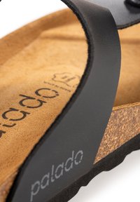 Sorte syntetiske sandaler med en korksål og gummisål. Har en struktureret strop og det synlige mærkenavn "palado" præget på sålen.