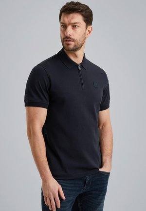 Polo shirt blu scuro in cotone, con maniche corte, colletto con zip e una piccola etichetta con il marchio sul petto.