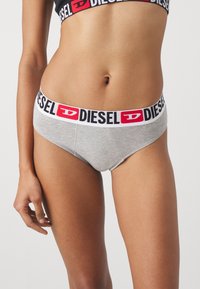 Grå bomullsboxershorts med en bred svart og hvit midjebånd med en rød "D" logo fra Diesel. Klassisk, glatt tekstur og lavt design.