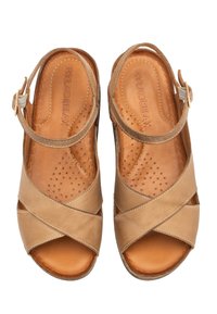 Brązowe skórzane sandały z krzyżującym się wzorem, otwartym noskiem i regulowanym paskiem na kostce. Teksturowana wkładka z perforacjami zapewniającymi wentylację.