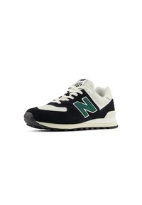 Baskets New Balance 574 en noir et blanc avec logo "N" vert et lacets blancs, angulées pour montrer le côté et le devant sur fond blanc.