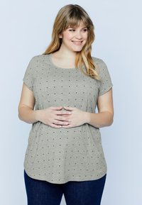 Camiseta corta de manga con un tono gris claro y un escote redondeado, con un patrón de puntos negros en toda la prenda y un corte relajado, con un dobladillo ligeramente curvado.