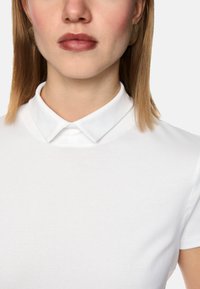 White polo shirt with a flat collar and short sleeves, featuring a soft, smooth texture and subtle stitching details.