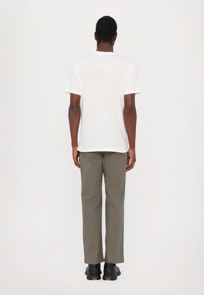 T-shirt blanc à manches courtes, pantalon vert olive, chaussures noires. Design simple, coupe décontractée, texture lisse. Pas de motifs ou d'accents notables.
