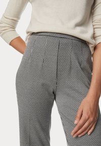 Pantaloni a vita alta in pattern houndstooth bianco e nero con pieghe, dotati di tasche laterali e un tessuto a trama liscia.