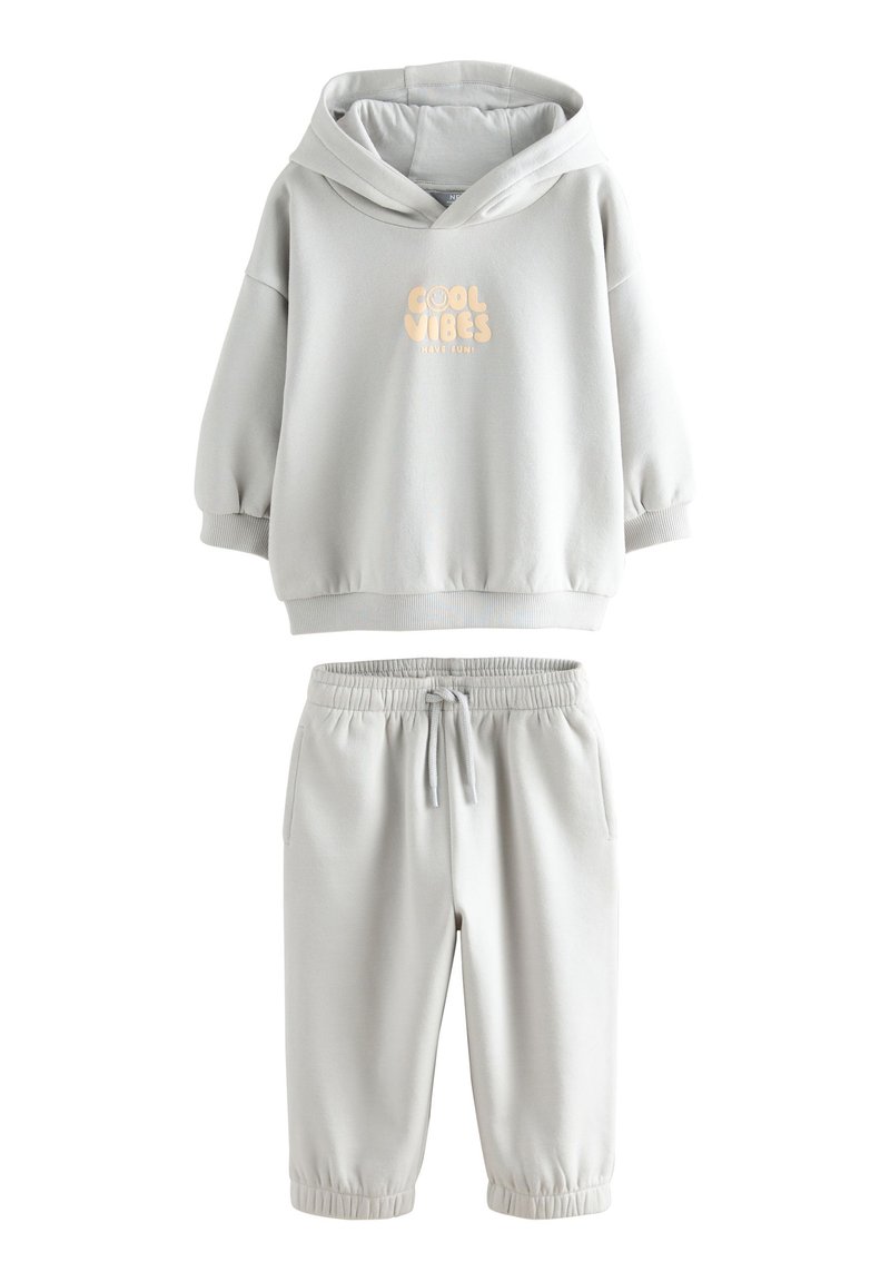 Felpa grigia con cappuccio e grafica testuale "Cool Vibes", abbinata a pantaloni jogger grigi coordinati con vita e polsini elasticizzati.