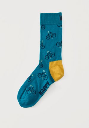 Chaussette bleue avec talon jaune présentant un motif de petits bicyclettes et le mot "HAPPY" près des orteils.