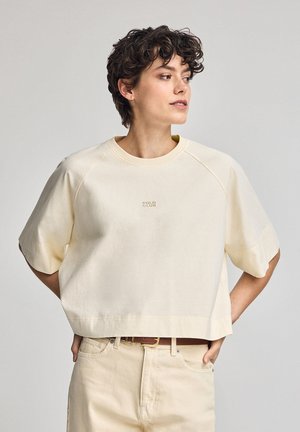 Felpa corta casual in crema chiaro, realizzata in tessuto morbido. Presenta maniche raglan e un discreto logo "POLO CLUB" sul davanti.