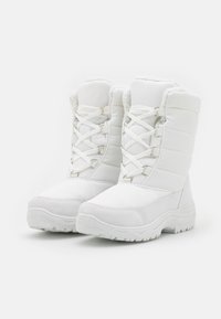 Bottes isolées blanches avec tige rembourrée, design à lacets, semelle texturée et accents en métal argenté. Matériau durable pour temps froid.