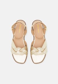 Χρυσά σανδάλια με λουριά, τετραγωνόσχημα και υφαντή λεπτομέρεια μπροστά. Μαλακή εσωτερική επένδυση και ρυθμιζόμενο λουρί στον αστράγαλο σε κομψό σχεδιασμό.