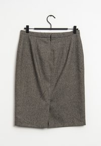 Grå tweed blyertskjol med en slits bak, dragkedjeslutning och en mjuk textur. Hänger från en svart galge mot en vit bakgrund.