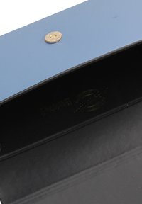 Scatola blu con una texture liscia e una chiusura a bottone dorato. Interno nero con un logo stampato in oro. Design semplice, forma rettangolare.