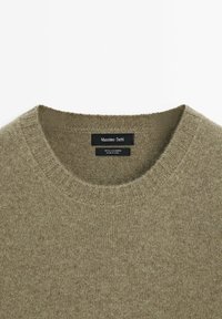 Olijfgroene crewneck kasjmier sweater met geribbelde kraag en zwart Massimo Dutti merklabel aan de binnenzijde van de halslijn.