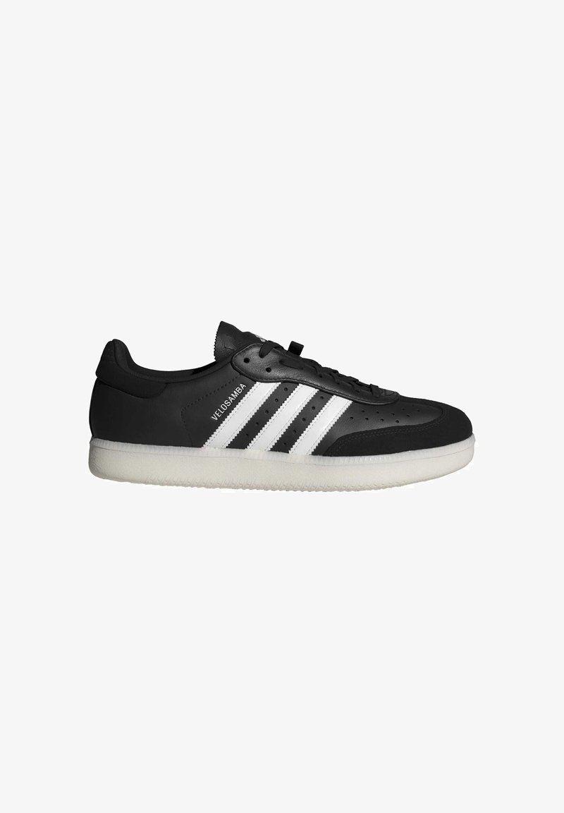 Czarne skórzane sneakersy z trzema białymi paskami, perforowana cholewka, sznurowane zapięcie oraz biała gumowa podeszwa z teksturowanym wzorem bieżnika.
