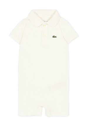 Biały krótki kombinezon niemowlęcy z krótkim rękawem, kołnierzykiem, dwoma guzikami z przodu oraz zielonym logo krokodyla na lewej piersi.