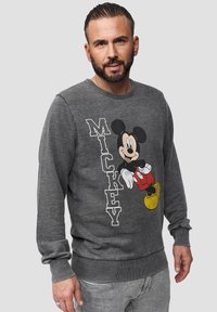 Šedá mikina s kulatým výstřihem má na přední straně ilustraci Mickey Mouse a text "MICKEY" v bílé barvě.