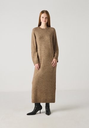 Long, brown knit dress with a crew neckline, full sleeves, and ribbed cuffs. Paired with black pointed-toe heeled boots.
