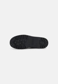 Semelle en caoutchouc noir avec des deep treads pour une meilleure adhérence. Semelles plates, forme arrondie et un design classique adapté à diverses activités de plein air.