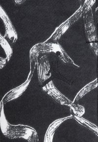 Svart stoff har hvite båndlignende mønstre med teksturert detaljering. En svart brodert Jumpman-logo er tydelig vist.
