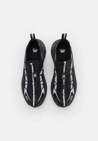 Czarne i szare buty sportowe z teksturowanym wierzchem, elastycznymi sznurowadłami i formowaną podeszwą z widocznym logo z boku i z tyłu.