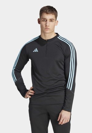 Haut de sport noir à manches longues avec col zippé, doté de trois bandes bleu clair sur les épaules et du logo Adidas sur le côté gauche.