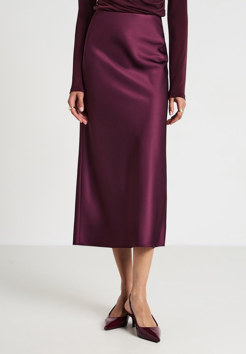 Gonna midi in satin bordeaux con una trama liscia e un'elegante caduta. Indossata con decolletè a punta in abbinamento. Design semplice e lineare.