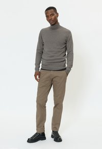 Pilka golfo megzta suknelė, apta figūra, derinama su smėlio spalvos chino kelnėmis ir juodais bateliais su raišteliais. Paprastos tekstūros, minimalios detalės ir neutralių spalvų.