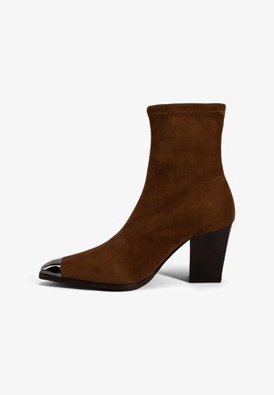 Brauner Wildleder-Stiefel mit engem Schaft, spitz zulaufender Spitze und glänzender schwarzer Kappenzehe. Verfügt über einen dicken, strukturierten Absatz für Halt.