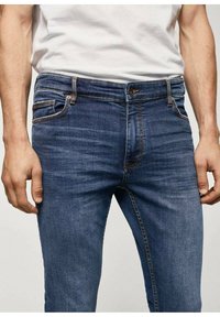 Tmavě modré denimové džíny slim fit, s zapínáním na zip, knoflíkovým zapínáním, pěti kapsami a kontrastním prošíváním.