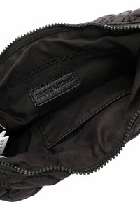 Sac à main noir en matelassé avec une fermeture éclair. L'intérieur présente une doublure en tissu noir lisse et une étiquette embossée avec "EMILY & NOAH."
