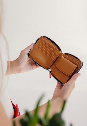 Tanzfarbener Leder Geldbeutel mit grauem Reißverschluss, ausgestattet mit mehreren Kartenfächern und einem Münzfach. Glatte Textur, minimale Markenkennzeichnung.