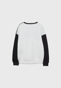 Sweatshirt met een wit lijf, zwarte lange mouwen, ronde hals en geribbelde manchetten. Glad stof met contrasterende kleurvlakken.