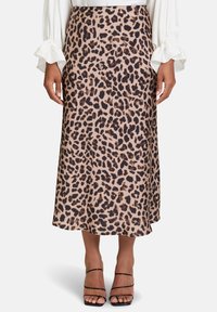 Leopardenmuster-Midirock aus einem leichten Stoff, in Beigetönen und Brauntönen mit schwingendem Saum, ergänzt durch schwarze Riemenhighheels.