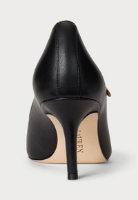 Melna ādas augstpēdu kurpe ar elegantu smailo purngalu, gludu tekstūru un šauru, paaugstinātu papēdi ar minimālām detaļām.