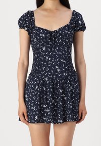 Námořnické květinové šaty s krátkými nabíranými rukávy, zpevněným živůtkem, čtvercovým výstřihem a rozšířenou sukní s bílými květinovými vzory.