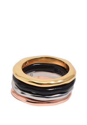 Anillos apilados en oro pulido, negro, plata y oro rosa con formas irregulares y orgánicas sobre un fondo blanco.